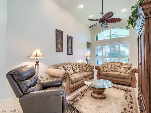 tiled living room with ceiling fan and a towering ceiling