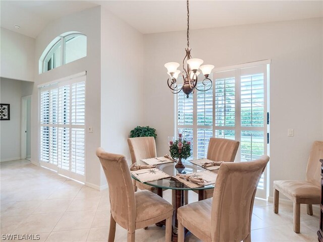 dining room featuring a notable chandelier, light tile patterned floors, and high vaulted ceiling