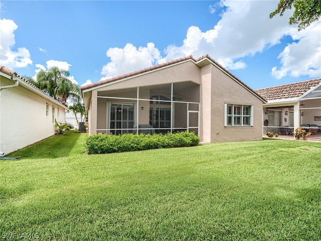 rear view of property with a yard, a sunroom, and central air condition unit