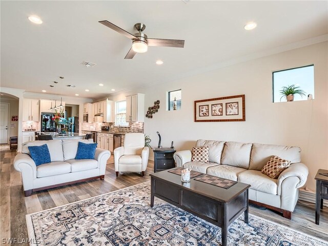 living room featuring crown molding, hardwood / wood-style floors, and ceiling fan