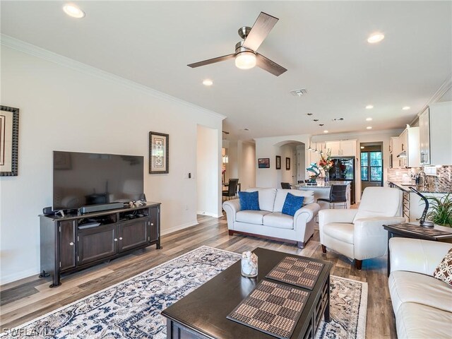 living room with ceiling fan, crown molding, and hardwood / wood-style flooring