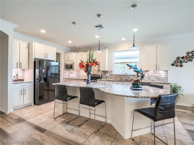 kitchen with appliances with stainless steel finishes, a center island, decorative backsplash, and light wood-type flooring