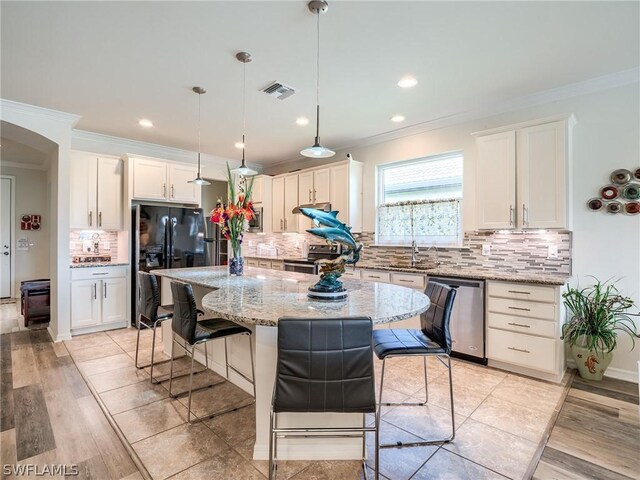 kitchen featuring a center island, appliances with stainless steel finishes, light hardwood / wood-style flooring, and decorative backsplash