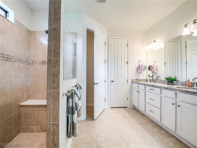 bathroom with tiled shower, double vanity, and tile patterned floors