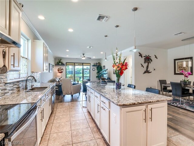 kitchen featuring decorative light fixtures, ceiling fan, crown molding, light wood-type flooring, and sink