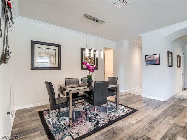 dining space with wood-type flooring and ornamental molding