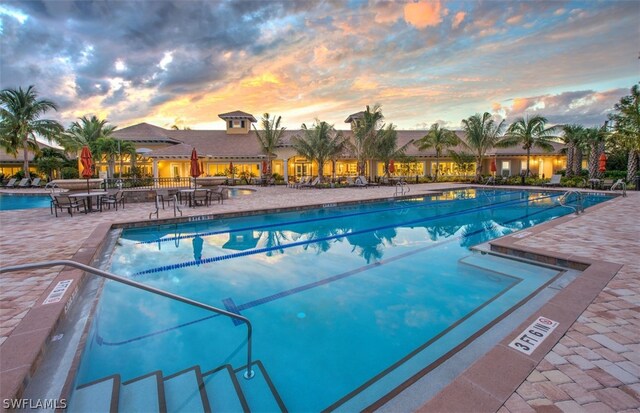 pool at dusk featuring a patio area