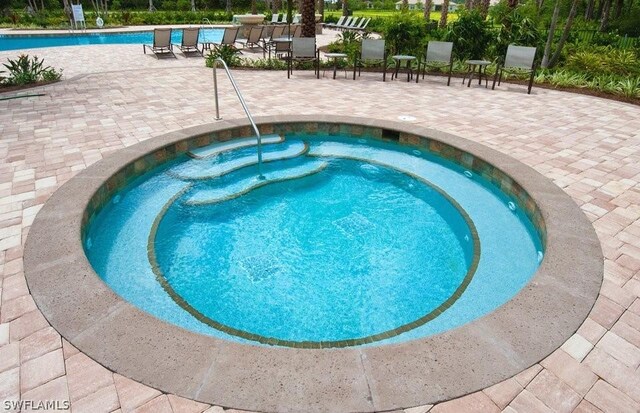 view of pool featuring a community hot tub and a patio