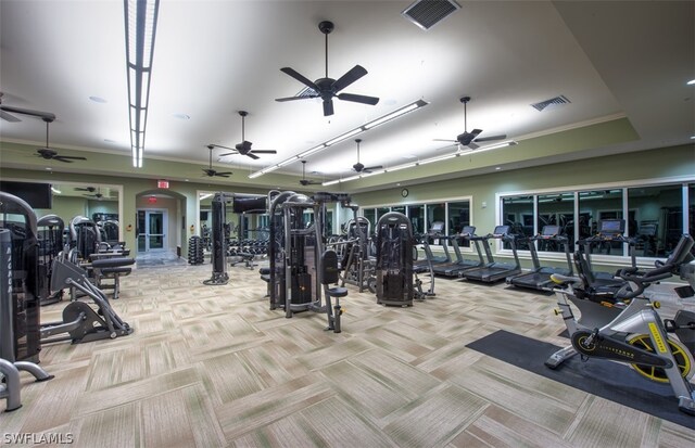 exercise room with light carpet, ceiling fan, and a tray ceiling