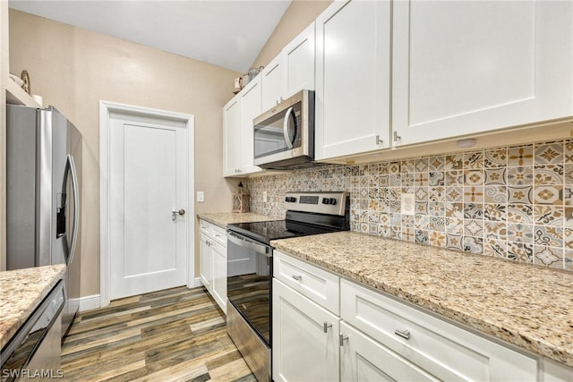 kitchen featuring appliances with stainless steel finishes, tasteful backsplash, hardwood / wood-style floors, light stone counters, and white cabinetry