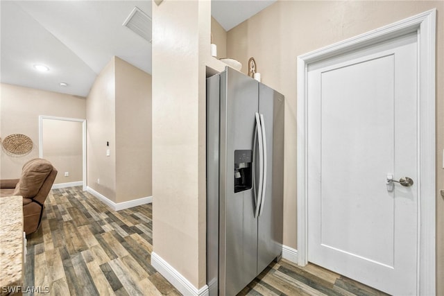 kitchen featuring light stone counters, wood-type flooring, and stainless steel fridge