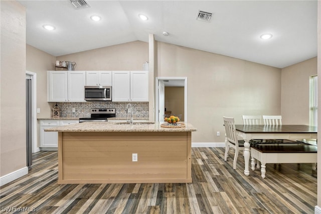 kitchen with backsplash, light stone counters, an island with sink, appliances with stainless steel finishes, and sink