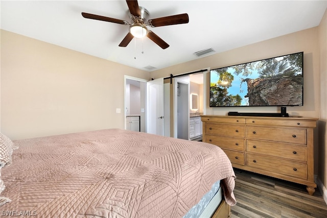 bedroom with dark hardwood / wood-style floors, a barn door, and ceiling fan