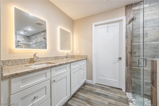 bathroom featuring walk in shower, dual vanity, and hardwood / wood-style floors