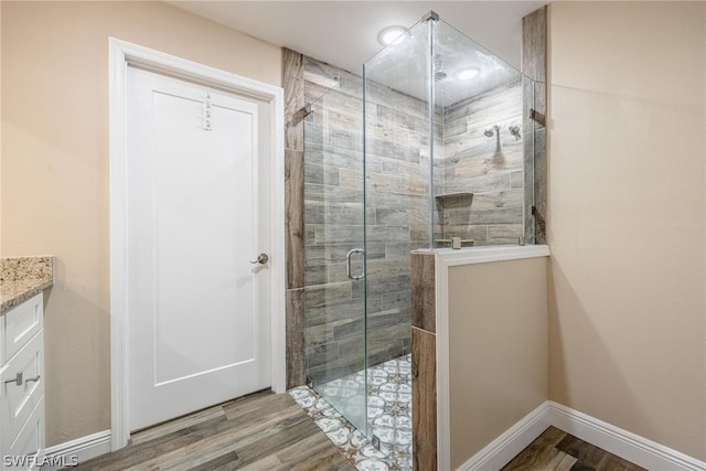 bathroom with wood-type flooring, a shower with shower door, and vanity