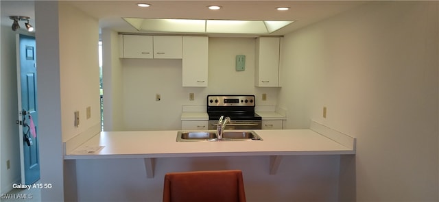 kitchen featuring sink, white cabinets, stainless steel electric range oven, and kitchen peninsula