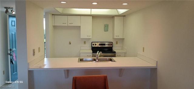 kitchen with white cabinetry, sink, stainless steel range with electric cooktop, and kitchen peninsula