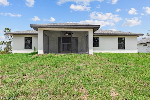 back of property with ceiling fan, a yard, and a sunroom