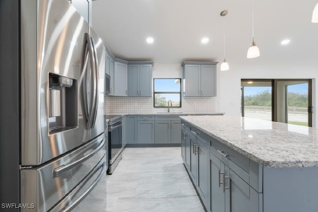 kitchen featuring pendant lighting, sink, stainless steel appliances, tasteful backsplash, and a kitchen island