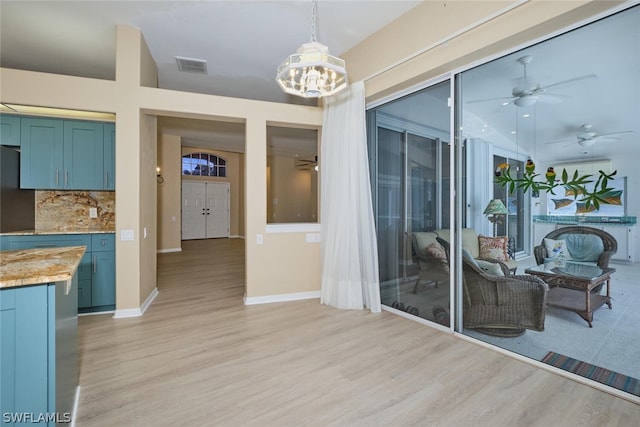 interior space featuring ceiling fan with notable chandelier and light hardwood / wood-style floors