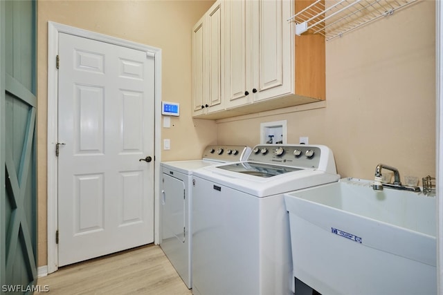 laundry area with washer and dryer, sink, cabinets, and light hardwood / wood-style flooring