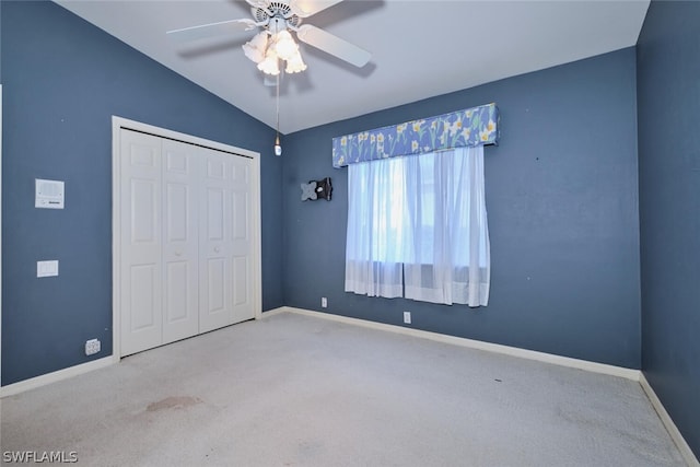 unfurnished bedroom featuring light carpet, lofted ceiling, a closet, and ceiling fan