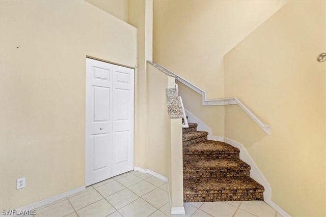 stairs featuring a towering ceiling and tile patterned floors