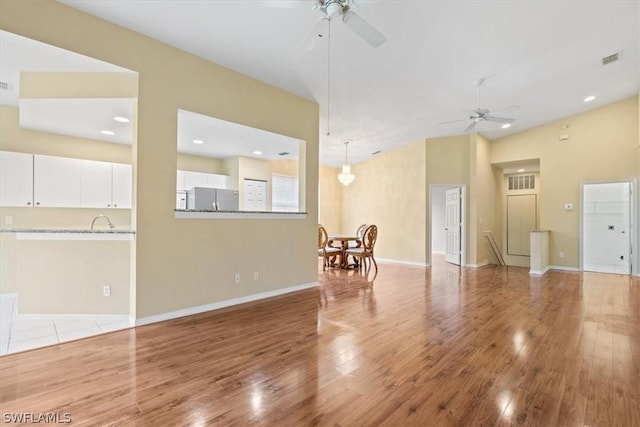 living room with vaulted ceiling, ceiling fan, and light hardwood / wood-style floors