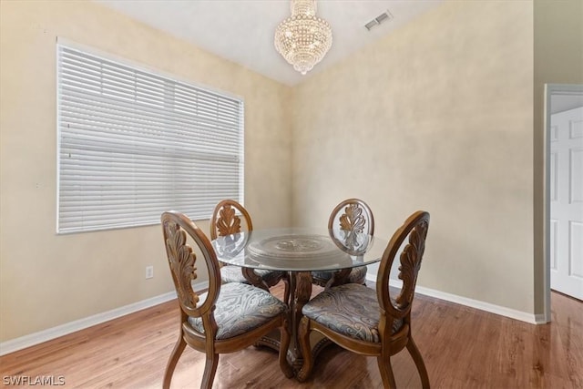 dining space with a notable chandelier and light hardwood / wood-style floors