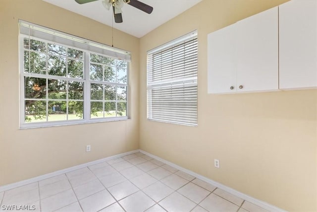 spare room featuring ceiling fan, light tile patterned flooring, and plenty of natural light