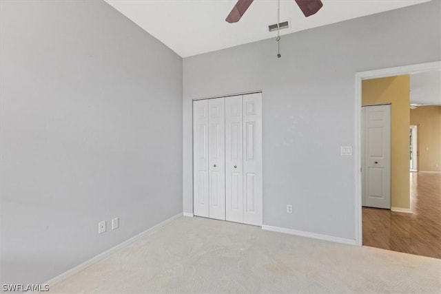 unfurnished bedroom featuring lofted ceiling, a closet, ceiling fan, and light colored carpet