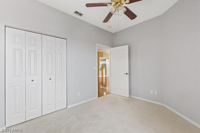 unfurnished bedroom featuring ceiling fan, a closet, and light carpet