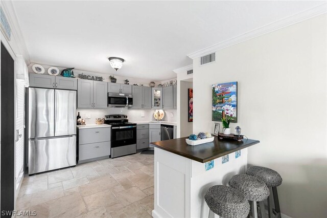 kitchen with gray cabinets, stainless steel appliances, tasteful backsplash, and kitchen peninsula