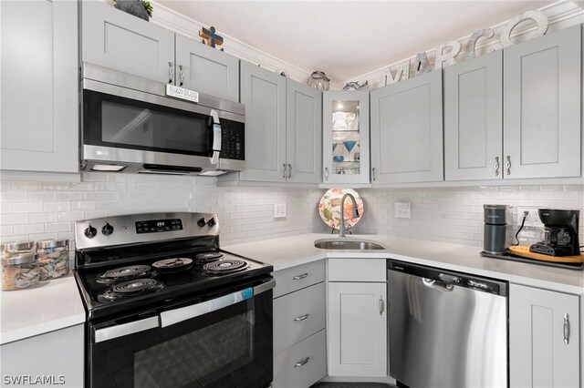 kitchen featuring decorative backsplash, stainless steel appliances, sink, and gray cabinets