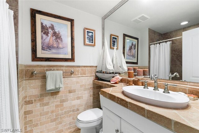 bathroom with vanity, tile walls, and toilet