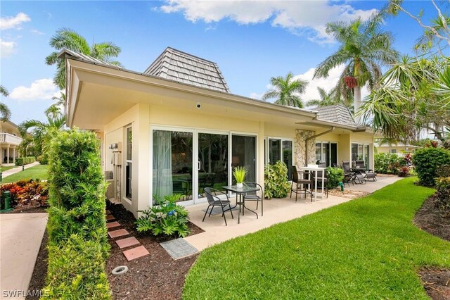 rear view of property featuring a patio and a lawn