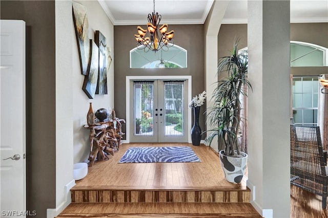 foyer featuring french doors, a notable chandelier, crown molding, and hardwood / wood-style flooring