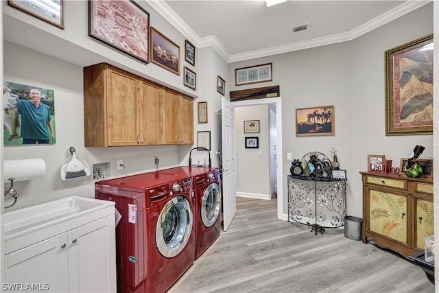 laundry area with sink, light hardwood / wood-style flooring, washer and clothes dryer, cabinets, and ornamental molding