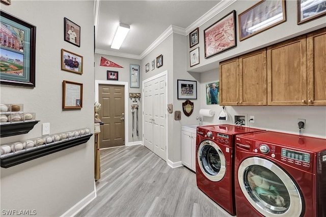 washroom featuring independent washer and dryer, crown molding, cabinets, and light wood-type flooring