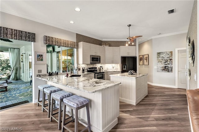 kitchen featuring light stone countertops, appliances with stainless steel finishes, a healthy amount of sunlight, and kitchen peninsula