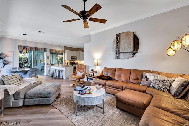 living room with wood-type flooring, ceiling fan, and crown molding