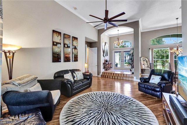 living room with dark wood-type flooring, a towering ceiling, crown molding, and a notable chandelier