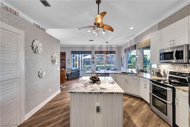 kitchen with white cabinetry, appliances with stainless steel finishes, decorative light fixtures, and crown molding