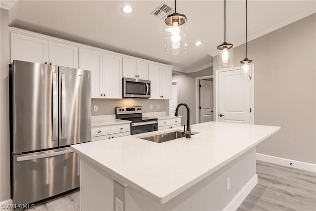 kitchen with stainless steel appliances, an island with sink, sink, and decorative light fixtures