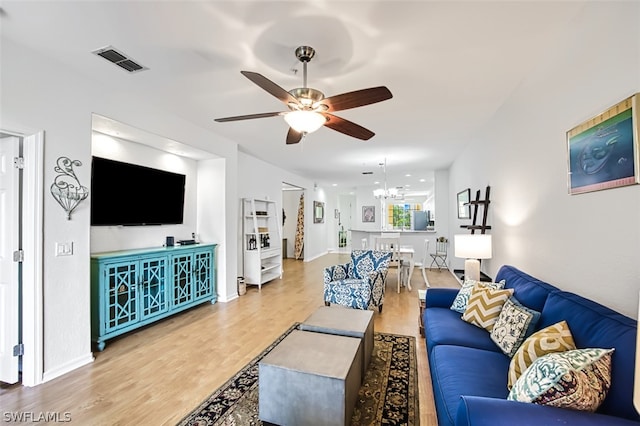 living room featuring ceiling fan with notable chandelier and light wood-type flooring