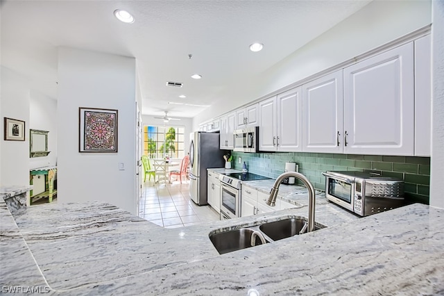 kitchen with light tile patterned floors, white cabinetry, stainless steel appliances, tasteful backsplash, and sink