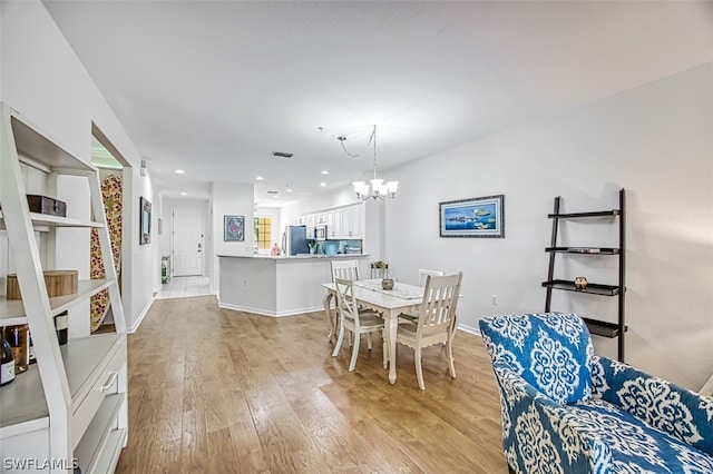 dining area with an inviting chandelier and light hardwood / wood-style flooring