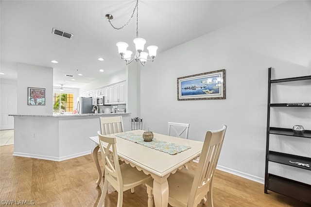 dining space featuring ceiling fan with notable chandelier and light hardwood / wood-style floors