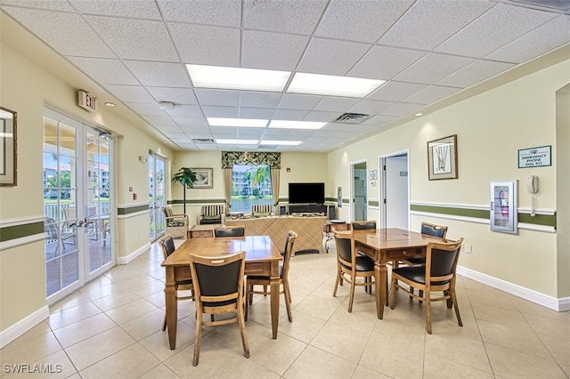 dining area featuring a wealth of natural light, a paneled ceiling, french doors, and light tile patterned flooring