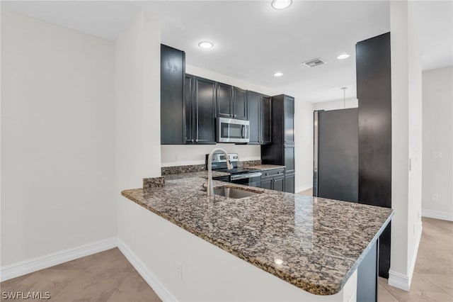 kitchen featuring dark stone countertops, light tile patterned flooring, kitchen peninsula, and appliances with stainless steel finishes